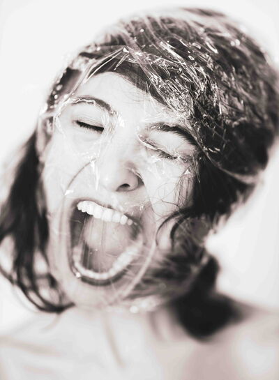 A woman is screaming while her head is wrapped in plastic foil. 