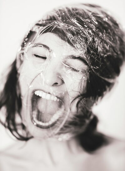 A woman is screaming while her head is wrapped in plastic foil. 